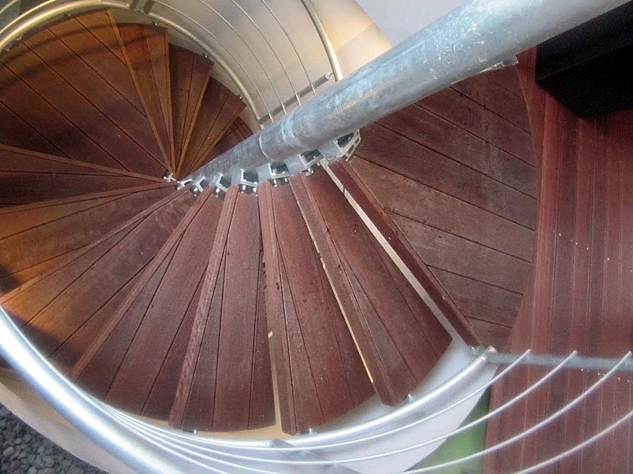 Točité dřevěné schodiště s kovovým zábradlím, pohled shora